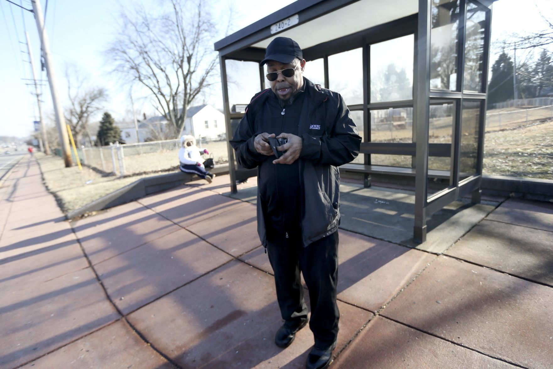 Antony Farmer waits for a bus after a court date in St. Ann